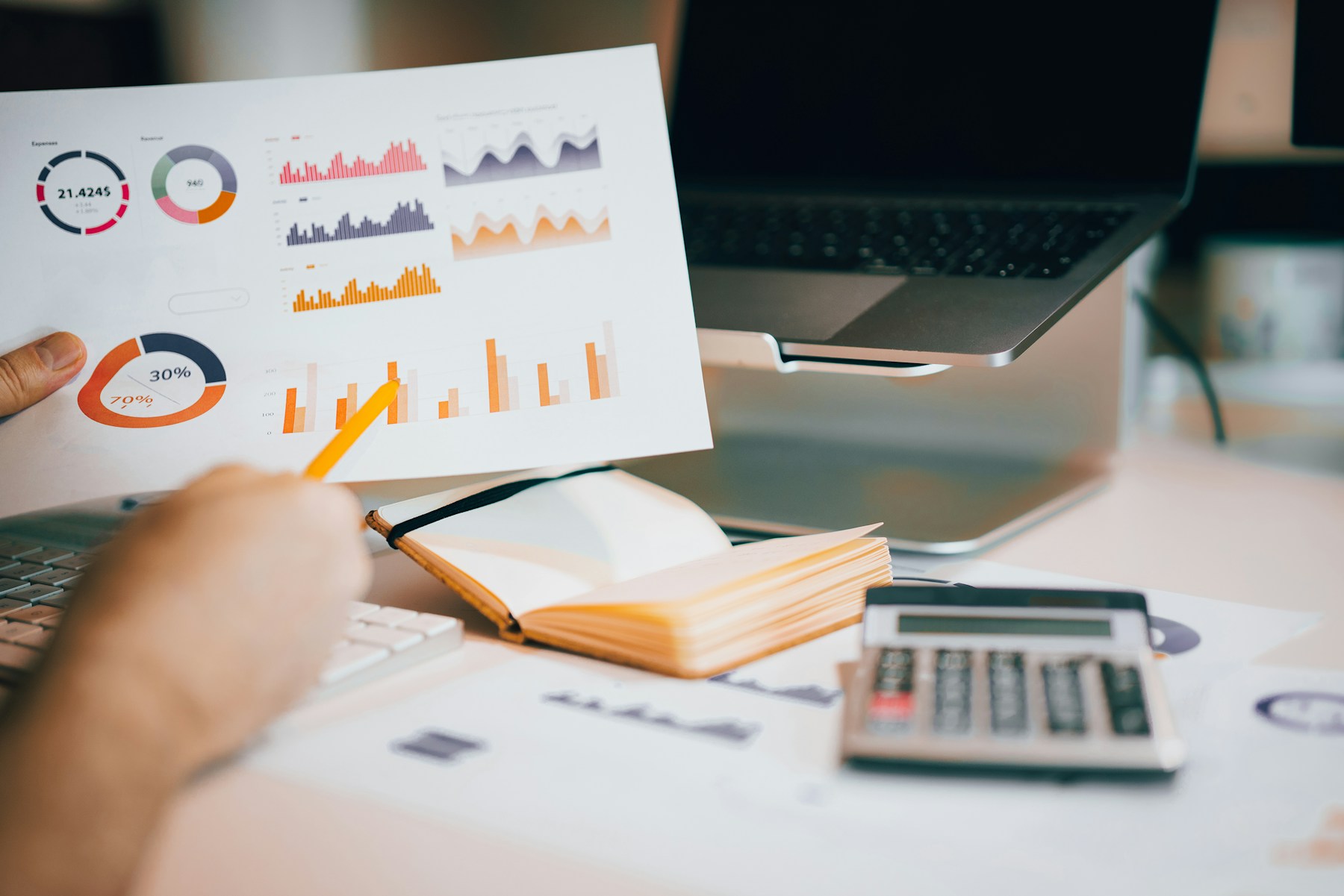 A business owner reviewing printed charts beside a laptop.