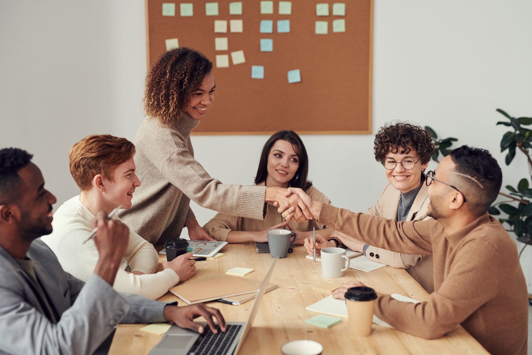 A group of adult creative professionals share ideas around a worktable.